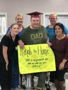 patient holding sign saying "Rehab to Home" with staff from Bourbon Heights