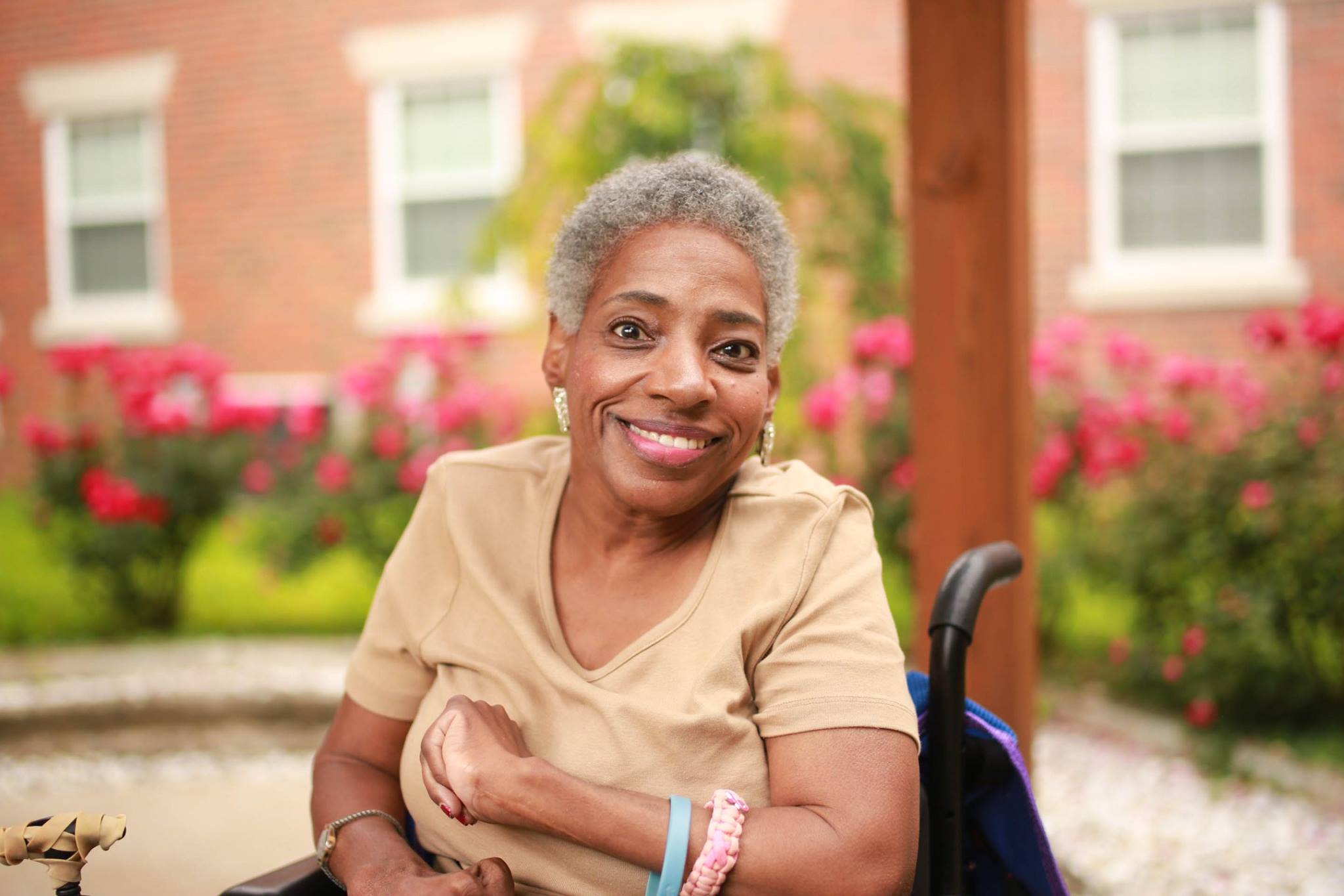 nursing home resident in wheelchair smiling with her arms folded