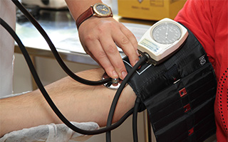 physician operating blood pressure cuff on arm