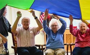 Residents of nursing home playing with a parachute while seated