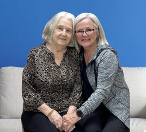 two women sitting on a couch with a blue background